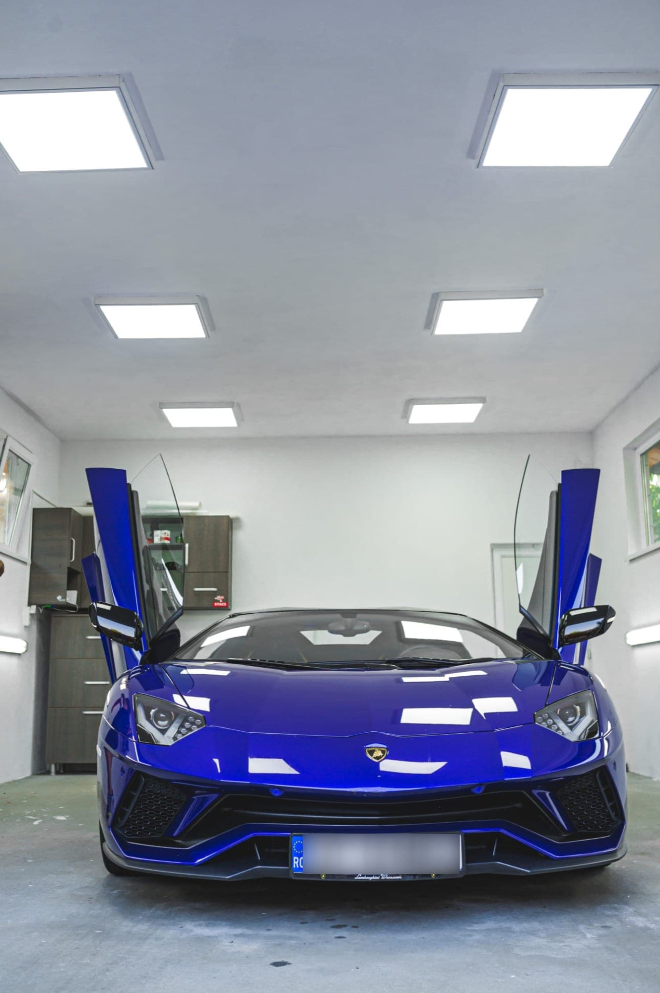 Atelierul Alpina, alb, cu un Lamborghini Aventador cu ușile ridicate