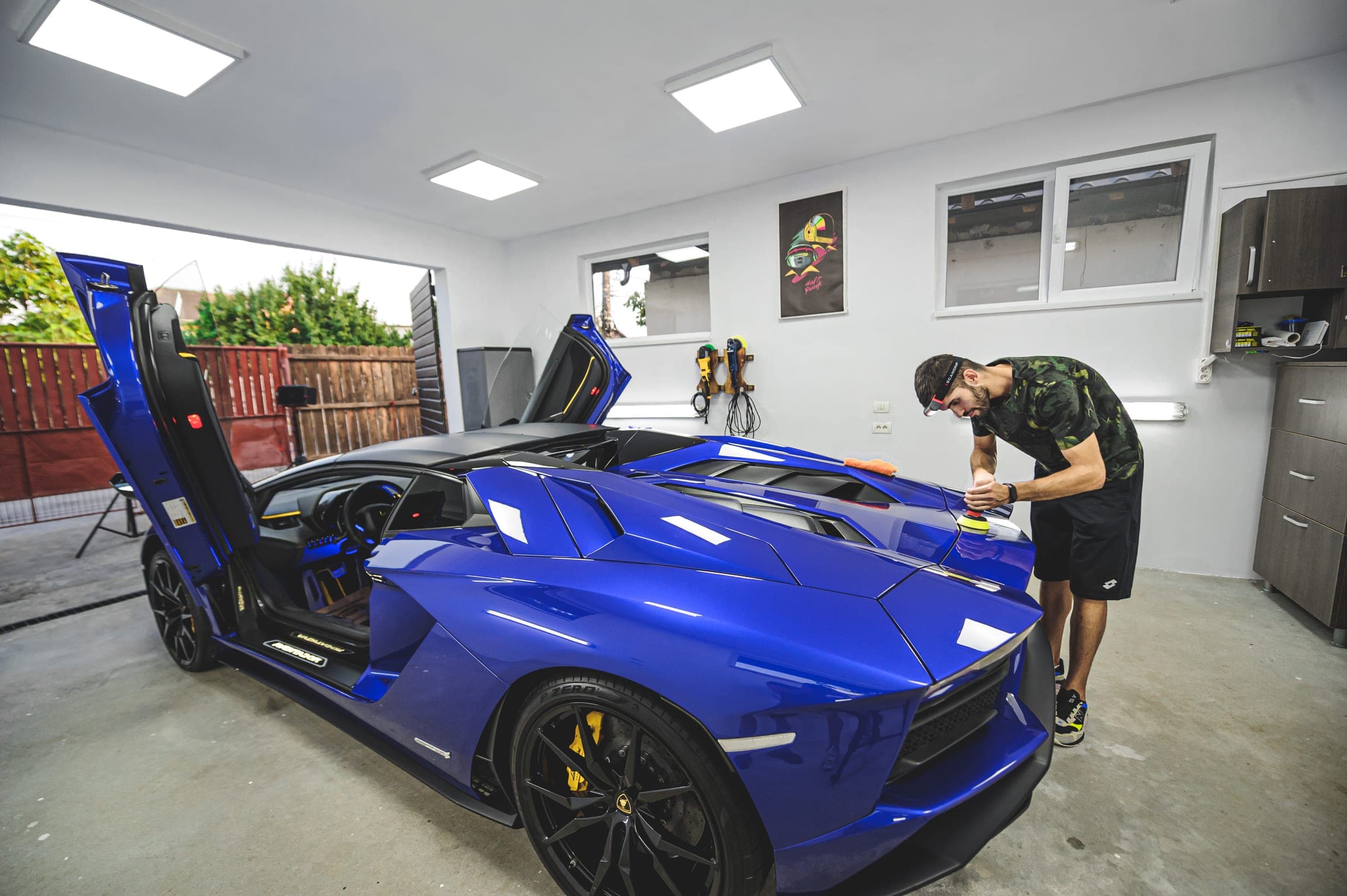 Tehnician Alpina lucrând la un Lamborghini Aventador albastru cu ușile ridicate