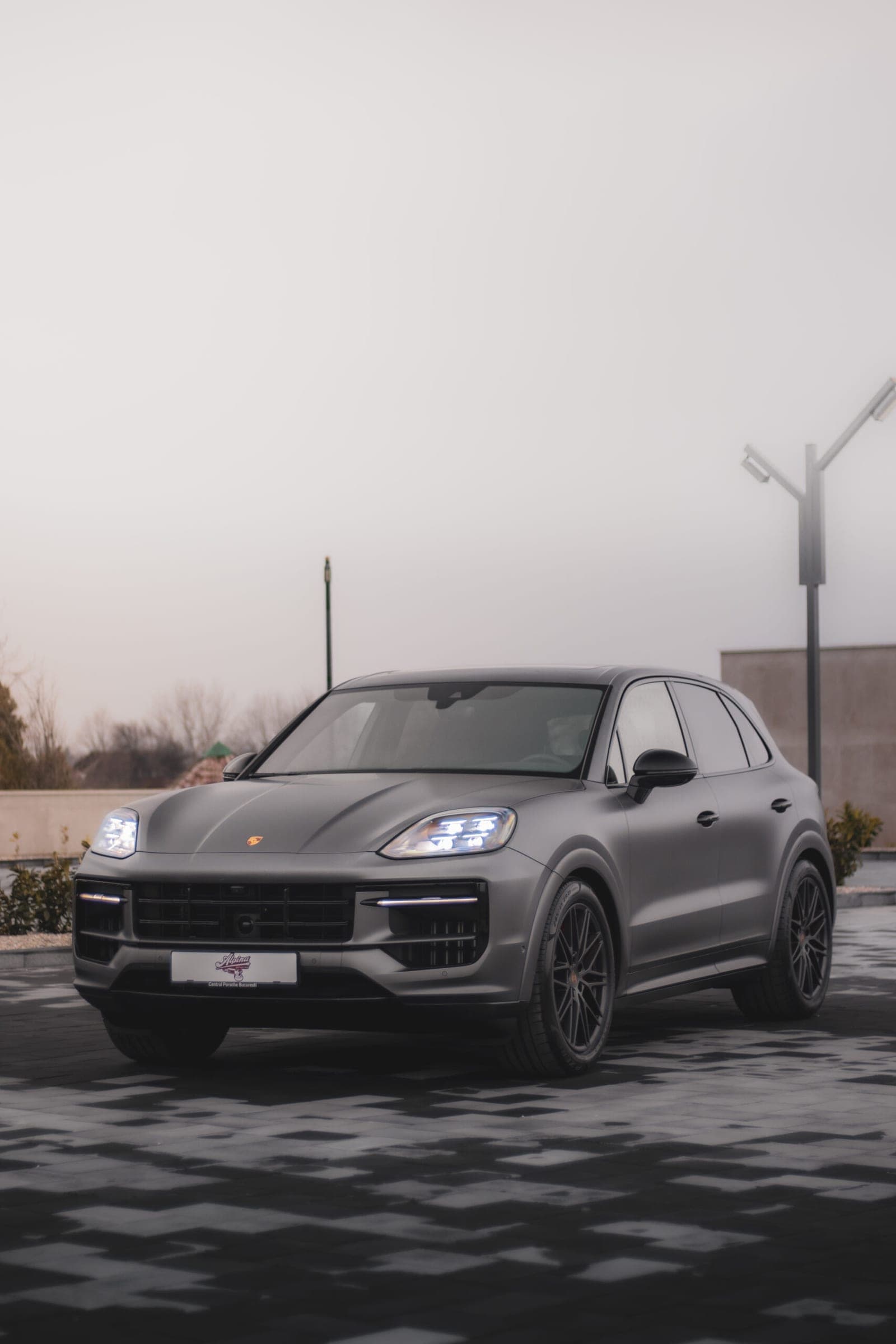 Porsche Cayenne gri pe un platou, cer înnorat