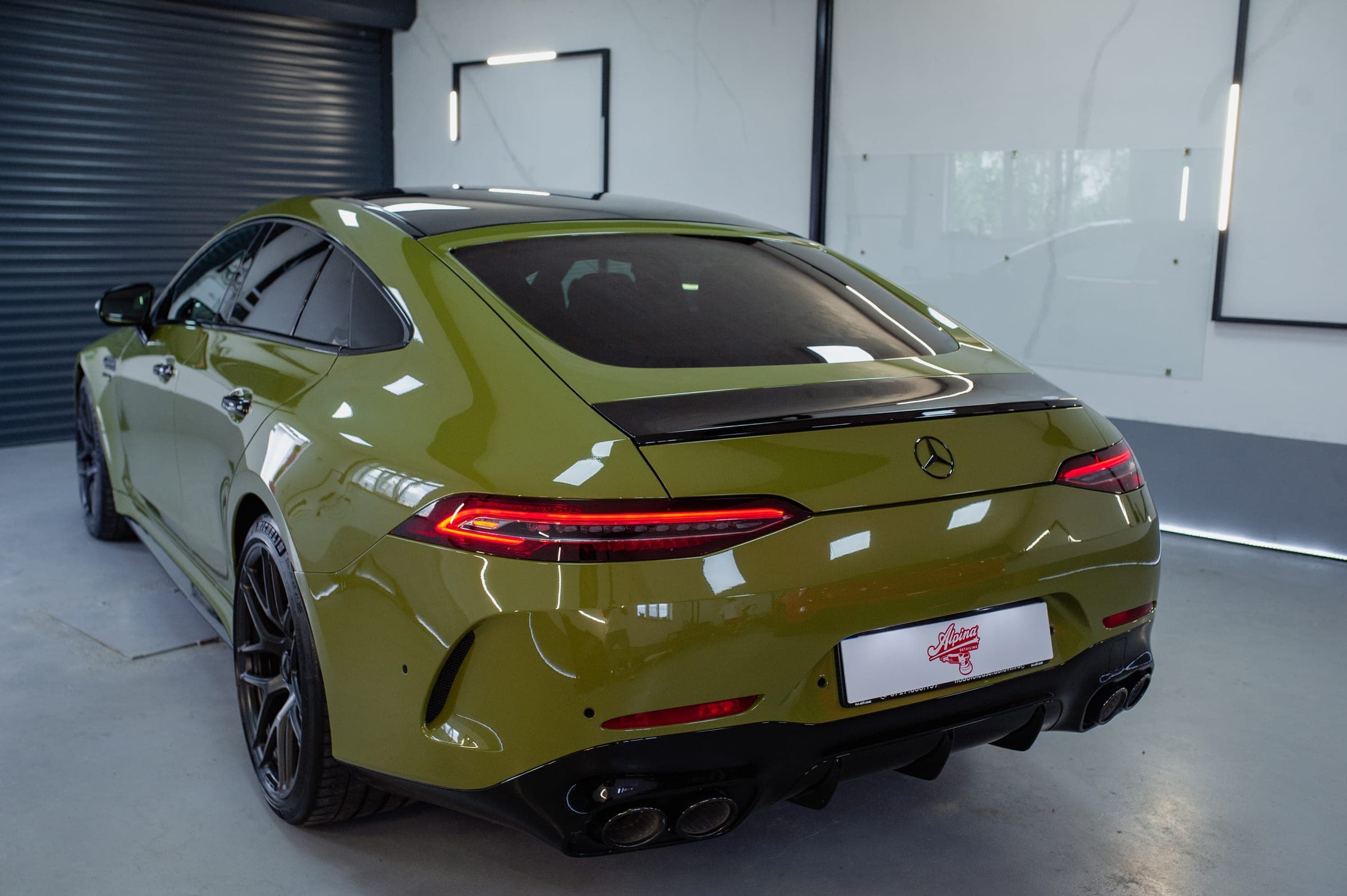 Spatele unui Mercedes-AMG GT 4 uși verde-oliv