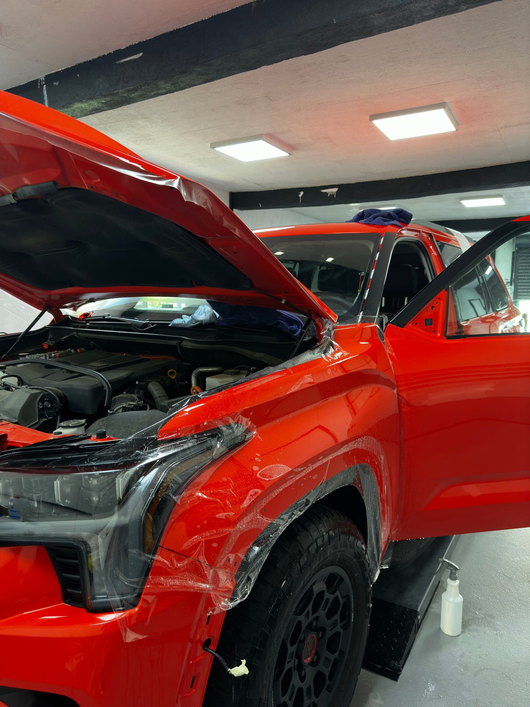 Toyota roșie cu capota ridicată, în timpul colantării